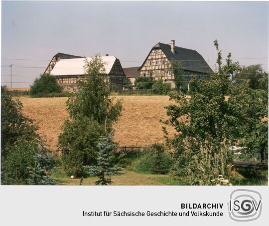 Blick über ein Feld zu einem Vierseitenhof in Lichtenstein