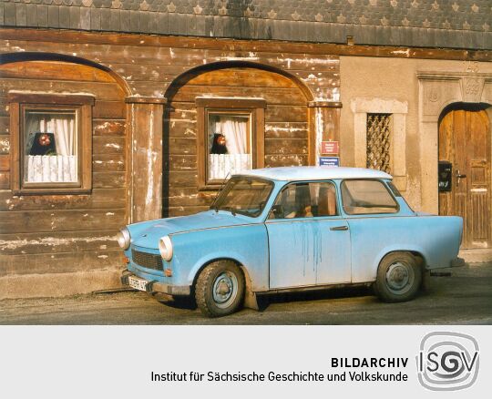 Blauer PKW Trabant vor einem Umgebindehaus in Ebersbach