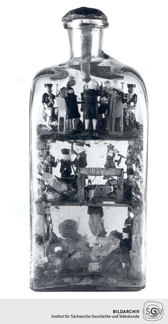 Glasflasche mit geschnitzten Darstellungen aus dem Bergmannsleben