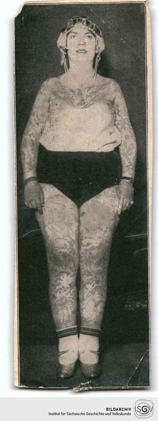 Zeitungsausschnitt mit eine Abbildung einer Körperkünstlerin (aufgeklebt)