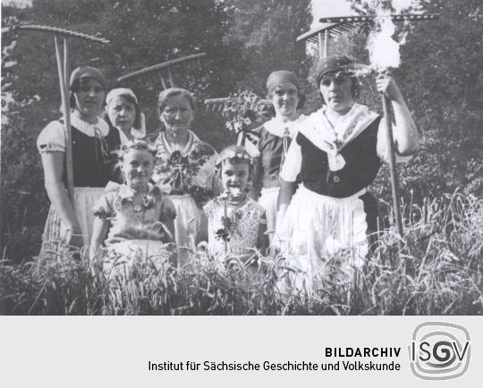 Frauen und Kinder in Tracht bei der Arbeit
