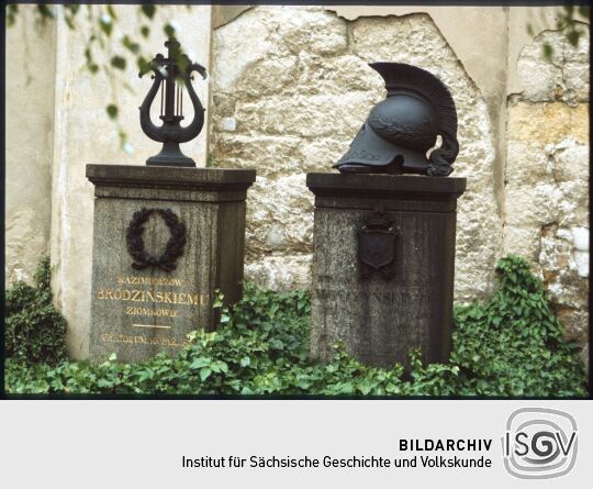 Zwei Gräber auf dem katholischen Friedhof in der Dresdner Friederichstadt. Die Grabsteine sind mit einer Lyra und einem antiken Helm geschmückt.