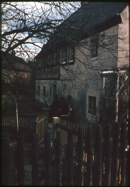 Gebäude in Reinhardtsgrimma, vor dem Haus sitzt eine Gruppe von drei Personen