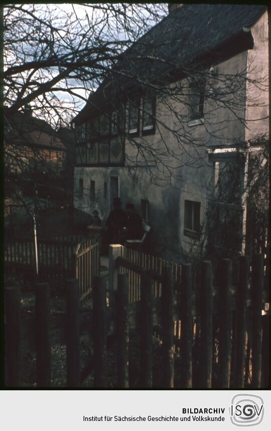 Gebäude in Reinhardtsgrimma, vor dem Haus sitzt eine Gruppe von drei Personen