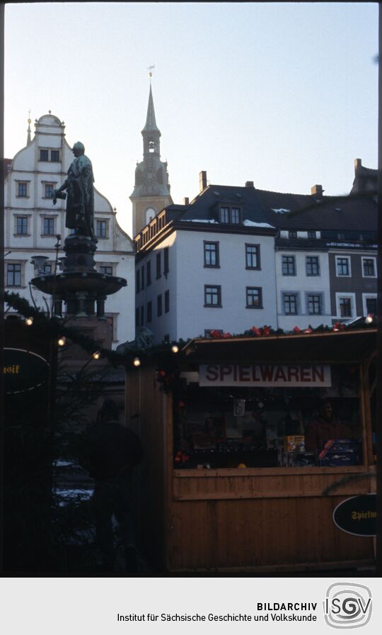 Verkaufsstand auf dem Freiberger Weihnachtsmarkt, im Hintergrund das Brunnendenkmal für Otto den Reichen und ein Turm der Petrikirche
