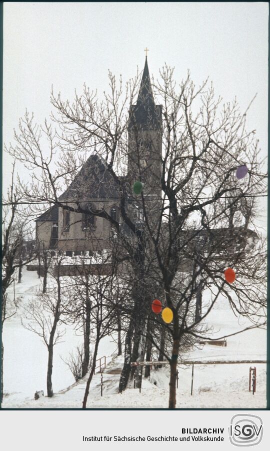 Blick zur Kirche im verschneitem Fürstenau, im Vordergrund ein mit Ostereiern geschmückter Baum
