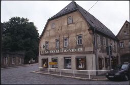 Bild: Fahnengeschmücktes Fachwerkgebäude mit einer Drogerie in Penig (Leipziger Straße 1)