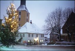 Bild: Verschneiter Marktplatz mit Weihnachtsbaum in Hohnstein in der Sächsischen Schweiz, im Hintergrund ist der Turm der Stadtkirche abgebildet