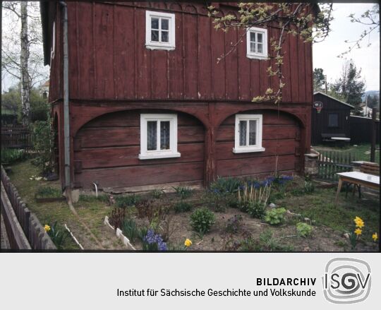 Umgebindehaus in Eibau mit Blumenbeeten und einem Basketballkorb im Hintergrund