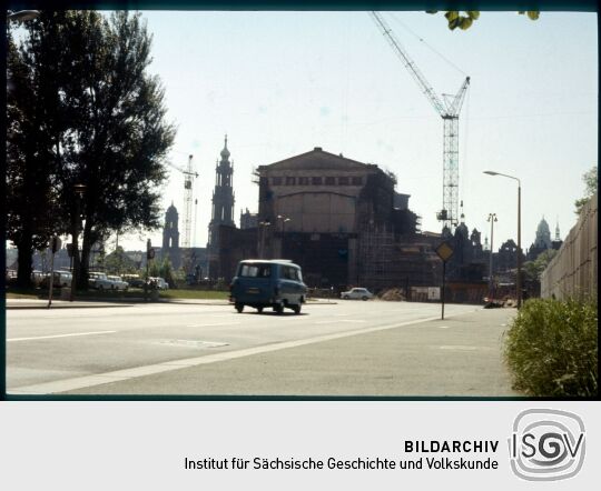 Blick auf die Westseite der Semperoper in Dresden während der Rekunstruktion und dem Bau der Erweiterungsbauten 1984. Im Hintergrund sind die Türme des Ständehauses, der Katholischen Hofkirche, des Schlosses und des Rathauses abgebildet.