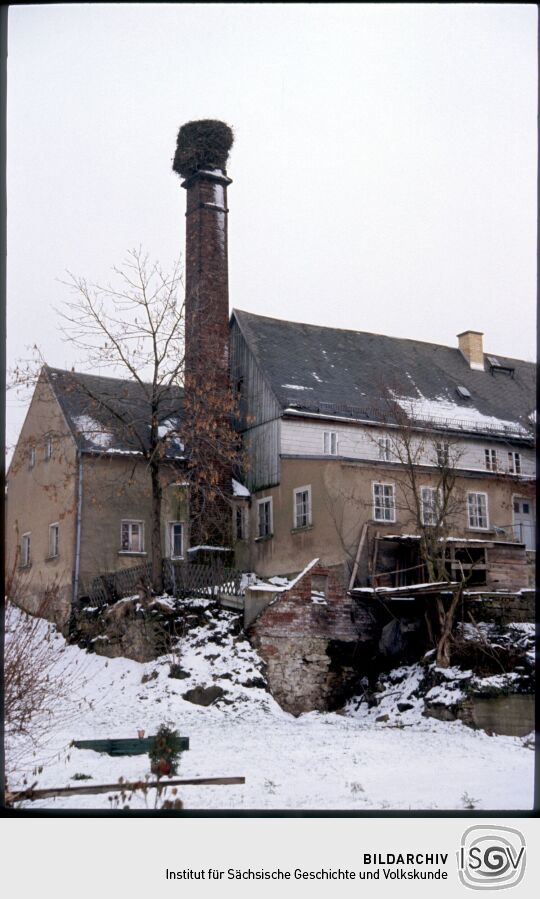 Verschneite Gebäude in Kleinröhrsdorf mit einem Storchennest auf einem Schornstein, 1993