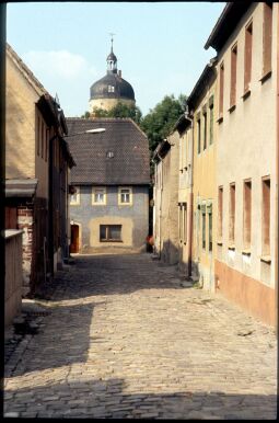 Bild: Blick durch die Badergasse in Mügeln mit dem Turm von Schloss Ruhethal im Hintergrund 1995