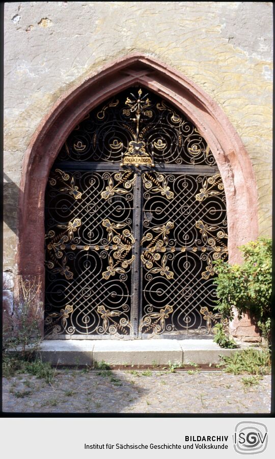 Portal zur Vorhalle der Kirche St. Johannis in Mügeln 1995. Das Portal ist mit einerm aufwändigen Schmiedeisernen Gittern (datiert auf das Jahr 1648) verschlossen.