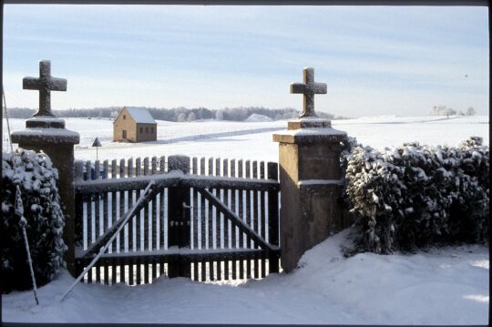 Blick durch das Friedhofstor in Kleinröhrsdorf auf verschneite Felder.