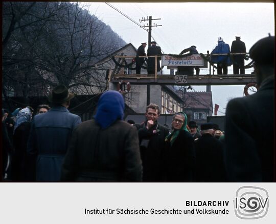 Umzug der Schifferfastnacht in Postelwitz 1959: Provisorische Brücke über eine Straße mit der Beschriftung 'Staustufe "Fortuna" Postelwitz'