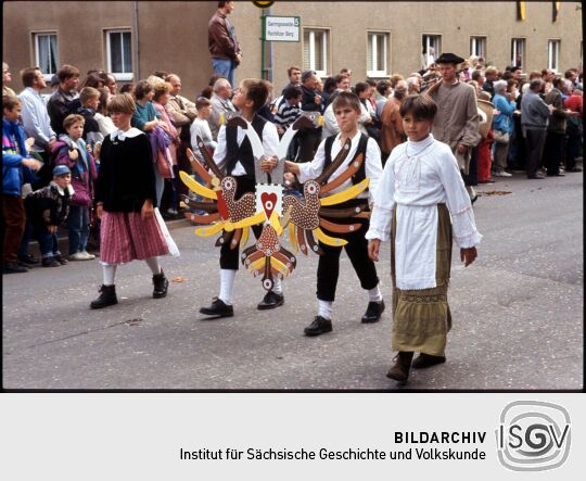 Kinder in historischen Kostümen mit einem Schützenvogel