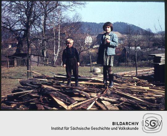 Zwei Kinder auf einem Holzstapel
