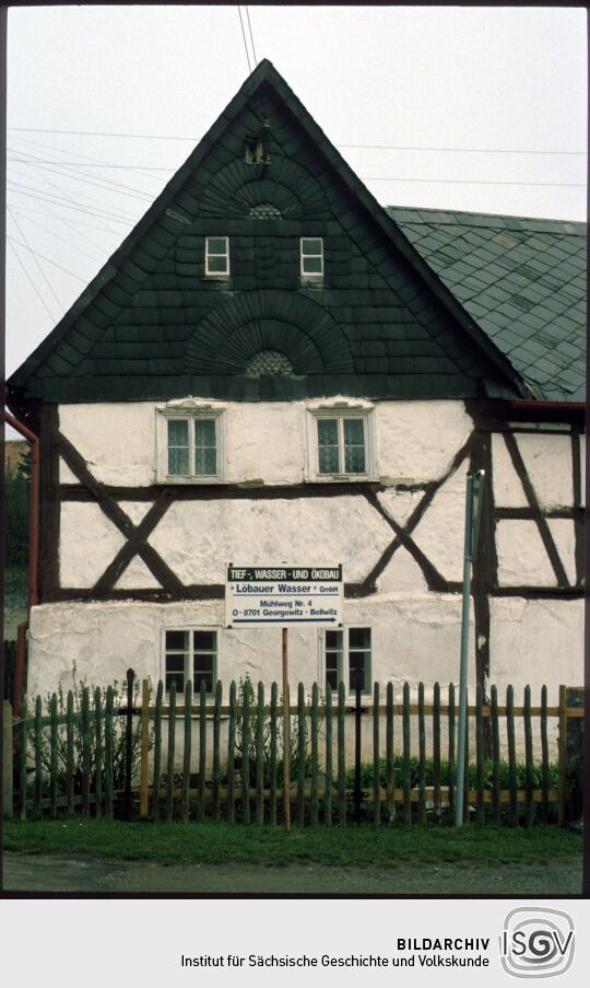 Werbeschild vor einem Fachwerkhaus mit verschiefertem Giebel