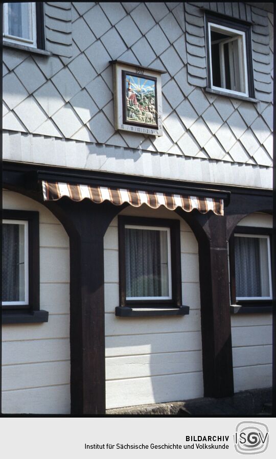 Sonnenuhr an der verschieferten Wand eines Umgebindehauses