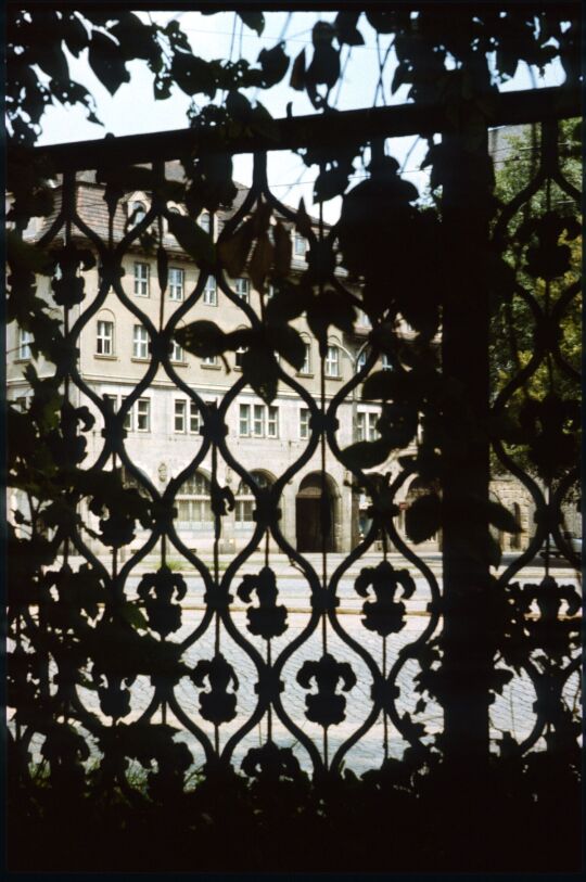 Blick durch ein Gitter des Eliasfriedhof zum Stadthaus Johannstasdt