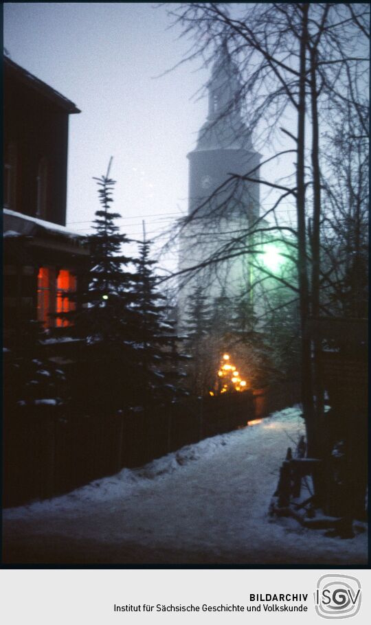 Blick durch das verschneite Schellerhau zur Kirche an Weihnachten