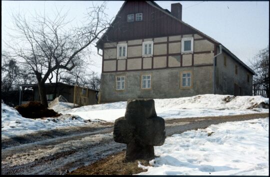 Sühnekreuz vor einem Fachwerkgebäude in Wünschendorf