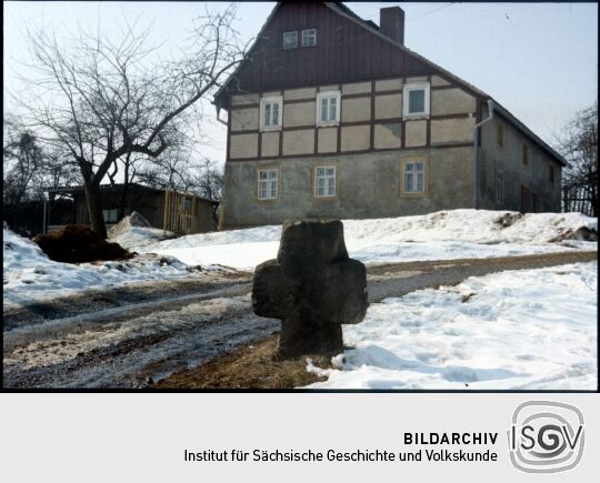 Sühnekreuz vor einem Fachwerkgebäude in Wünschendorf