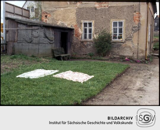 Textilien auf einer Wiese vor einem Gebäude in Eibau