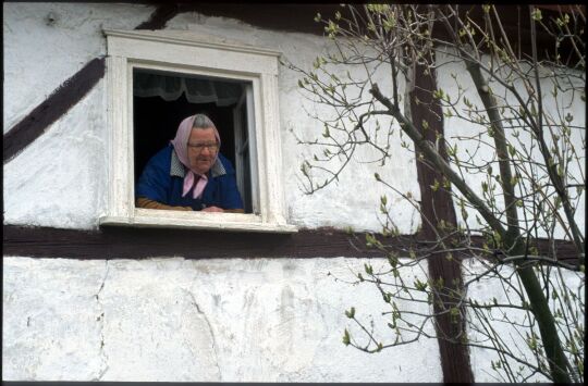 Frau mit Kopftuch an einem Fenster in Georgewitz