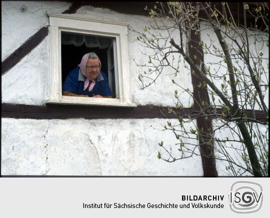 Frau mit Kopftuch an einem Fenster in Georgewitz