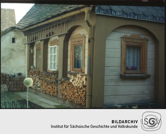 Umgebindehaus in Waltersdorf mit Brennholzvorräten und Leiter