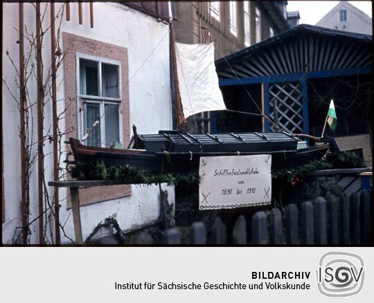 Ein historisches Schiffsmodel vor einem Haus in Bad Schandau, wahrscheinlich während der Schifferfastnacht aufgenommen