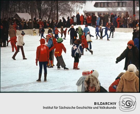 Zum Teil verkleidete Eisläufer auf der Eisbahn in Geising