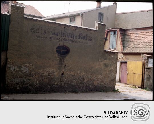 Historisches Geschäftsschild an einer Mauer in Bischofswerda