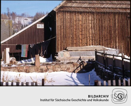 Wäsche an einer Leine neben einer holzverkleideten Scheune in Geising