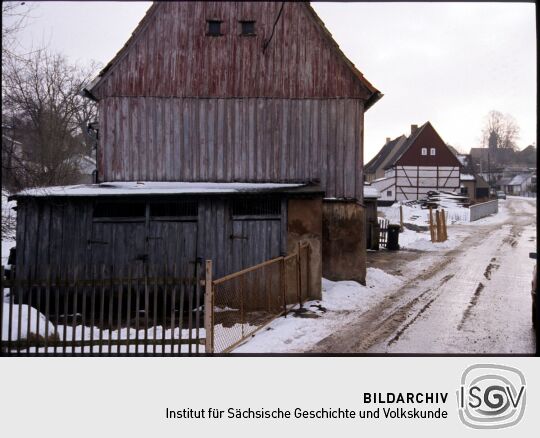 Blick durch die verschneite Röderstraße in Großröhrsdorf mit der Kirche im Hintergrund.