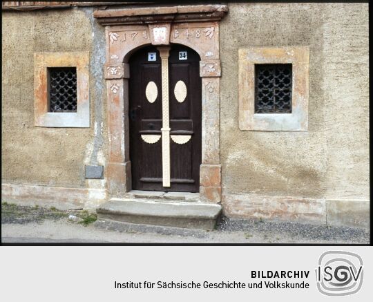 Haustür an einem Gebäude in Jonsdorf mit barocker Steineinfassung und klassizistischem Türblatt