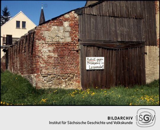 Protestschild gegen eine Mülldeponie am Tor einer zum Teil verfallenen Scheune in Leppersdorf