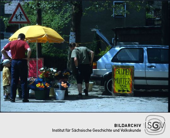 Verkaufsstand für Blumen an einer Straße, die Werbung nimmt Bezug auf den Muttertag