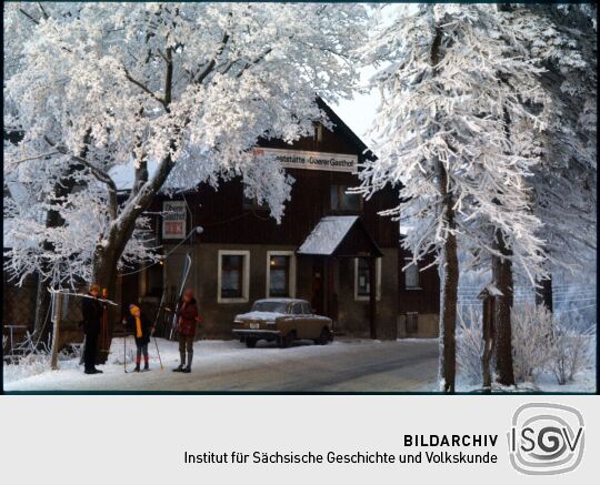 Skiläufer vor derverschneiten Oberern Gasthof in Schellerhau