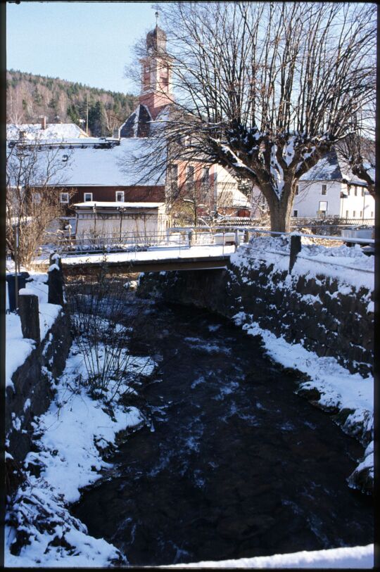 Blick über den Pöbelbach zur Kirche in Schmiedeberg im Winter