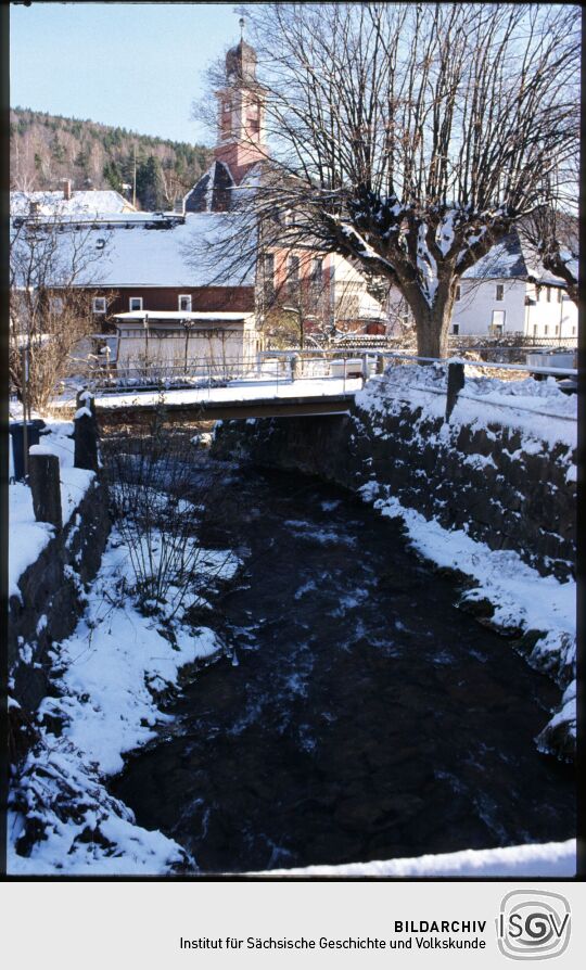 Blick über den Pöbelbach zur Kirche in Schmiedeberg im Winter