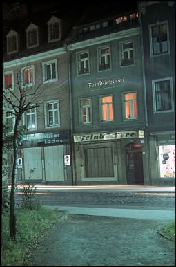 Bild: Zwei Gebäude in der Dresdner Heinrichstraße mit einem Optikergeschäft und deiner Feinebäckerei bei Nacht