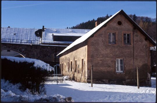 Verschneites Gebäude vor dem Eisenbahnviadukt in Schmiedeberg