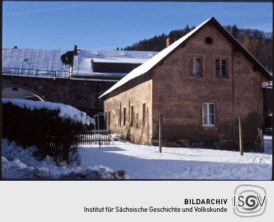 Verschneites Gebäude vor dem Eisenbahnviadukt in Schmiedeberg