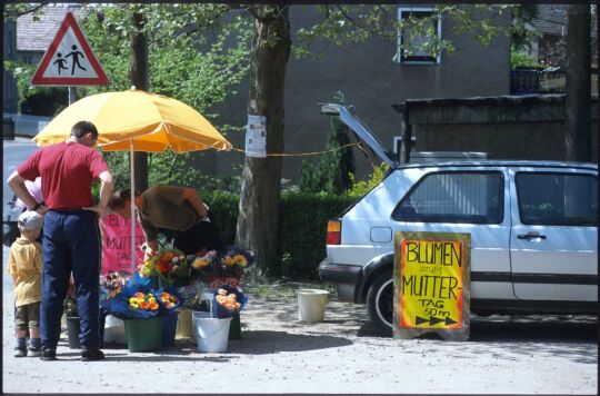 Verkaufsstand für Blumen an einer Straße, die Werbung nimmt Bezug auf den Muttertag